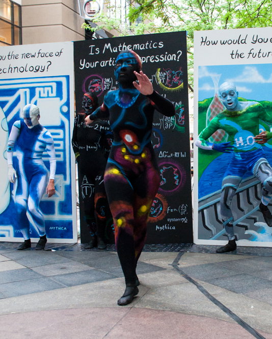 Painted dancer dancing in the street in front of the STEM panels
