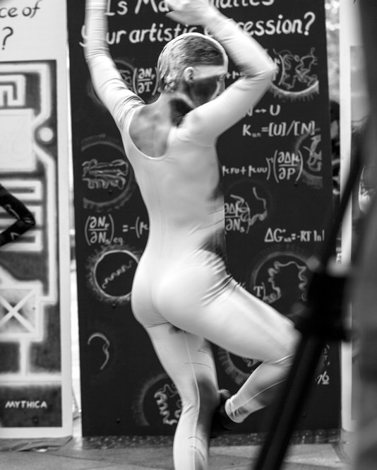 Black and white photo of the technology dancer pirouetting in front of the math panel